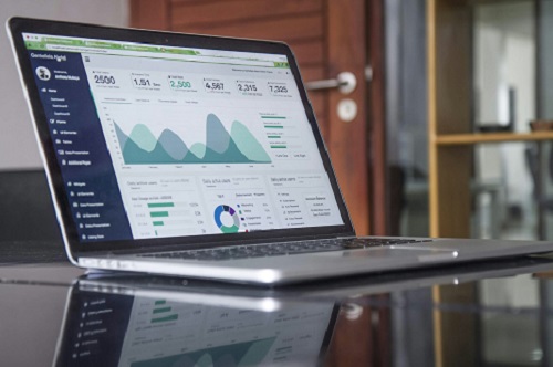 A photo of a laptop with graphs and charts on the screen